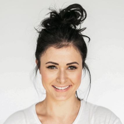 A young woman with black hair in a bun smiling at the camera