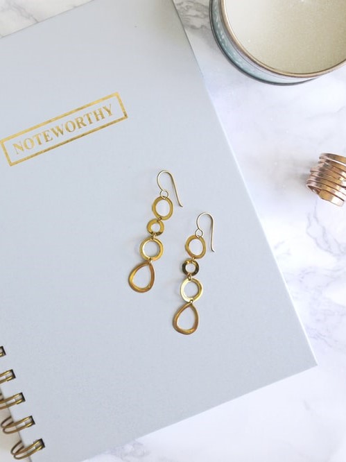 A pair of long golden earings on a notebook